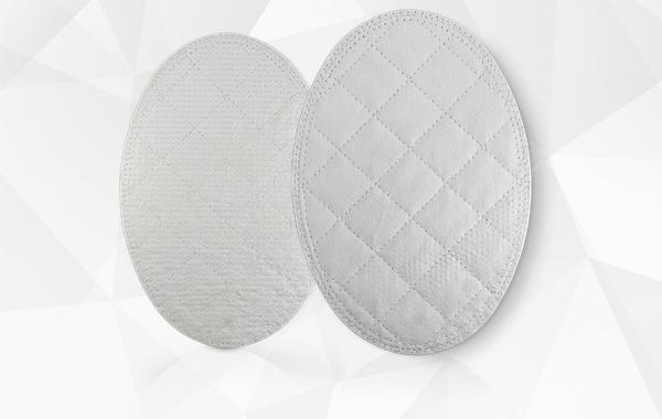 Two oval pads of reinforced tissue matrix, one quilted with a diamond stitch and one with a fine tight stitch, on a faceted white background